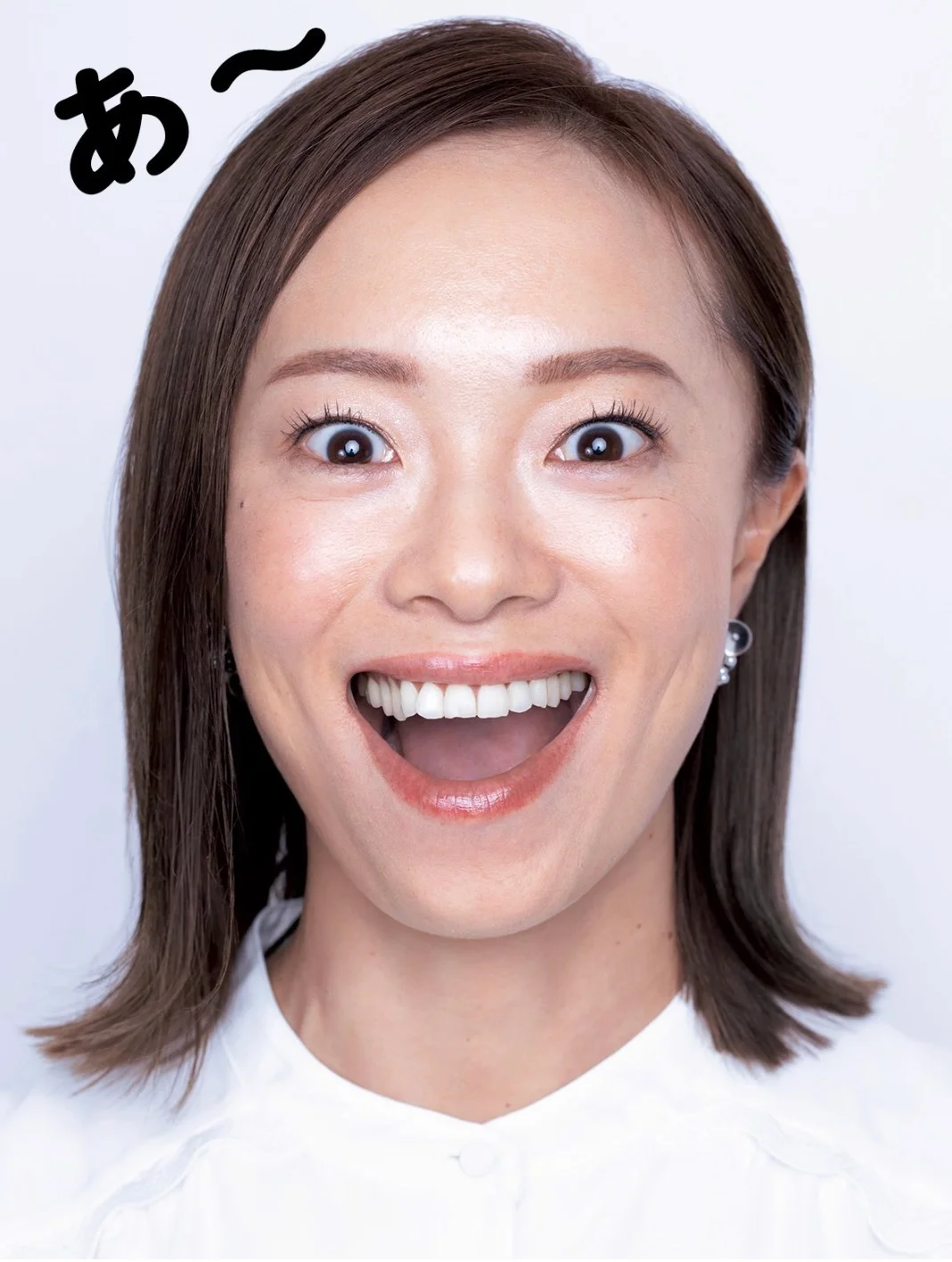 「あ」のポーズの実演。指を縦にして口に入れ口角を上げる